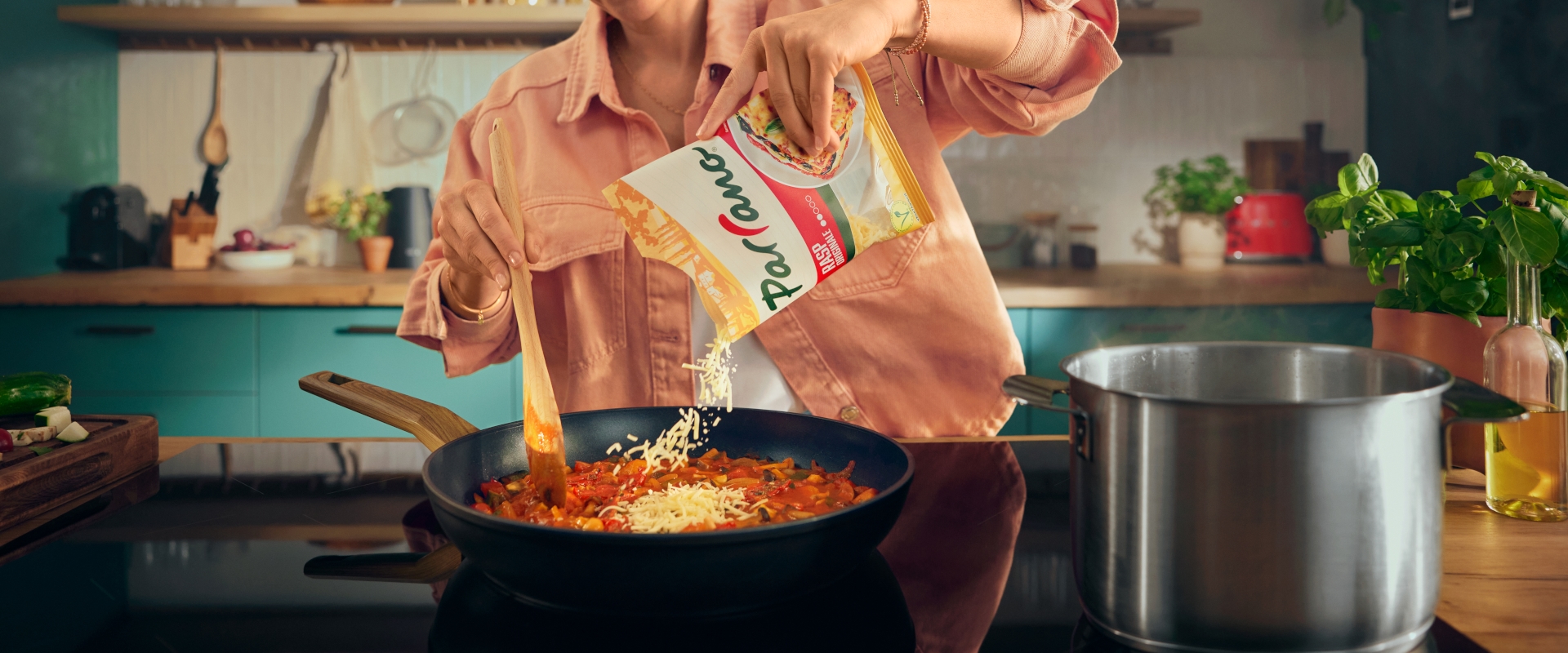 Vrouw staat in de keuken mozzarella te snijden voor op een pizza.
